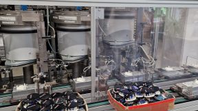 Bilder aus der Werksführung und Produktion von Lorenz Meters, Hersteller für Wasserzähler. Im Hintergrund Maschine, davon zwei Kisten mit alten Wasserzählern
